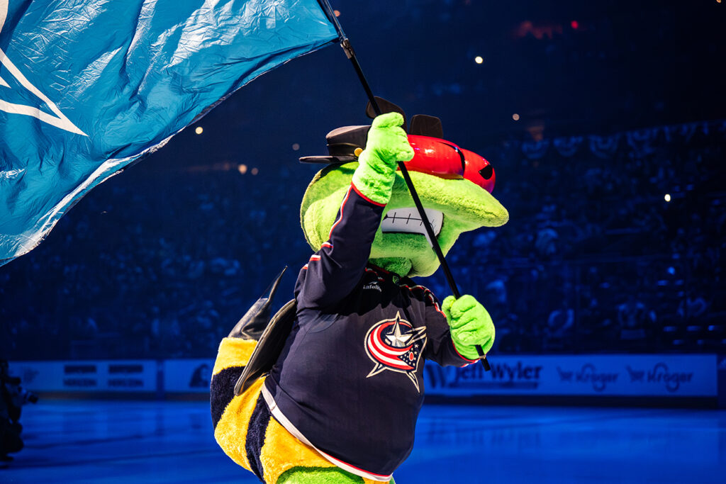 Blue Jackets mascot Stinger skating with logo flag