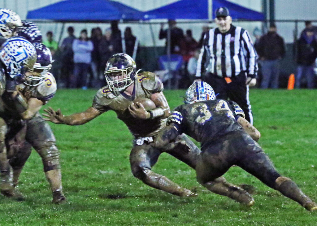 East Knox's Blake Elliott runs in mud