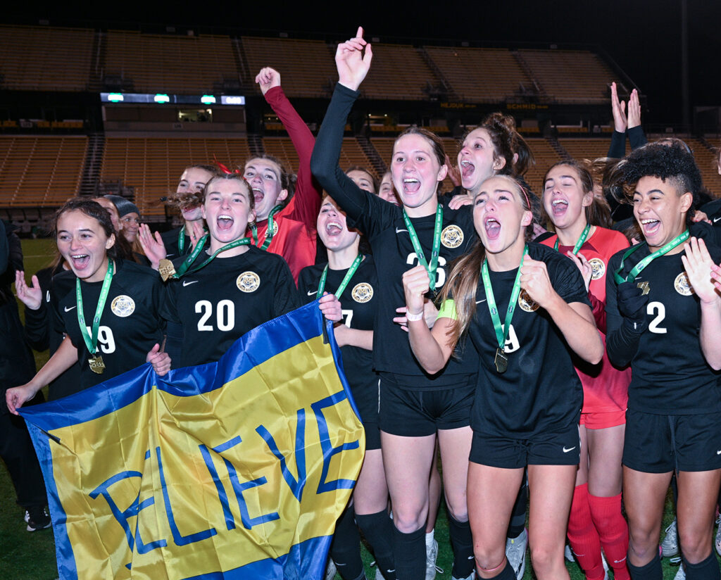 UA girls soccer team with BELIEVE banner
