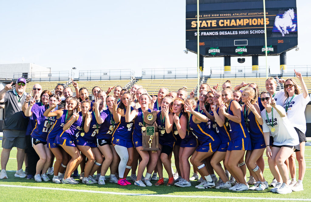 DeSales with trophy in front of scoreboard
